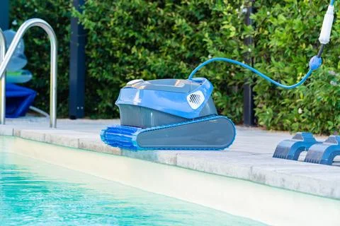 Automatic Pool Cleaner by the Poolside with Garden Background Foto stock