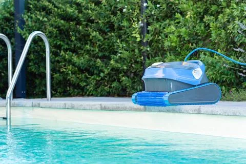 Automatic Pool Cleaner by the Poolside with Garden Background Foto stock