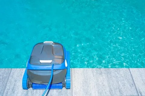 Automatic Pool Cleaner by the Poolside with Garden Background Foto stock