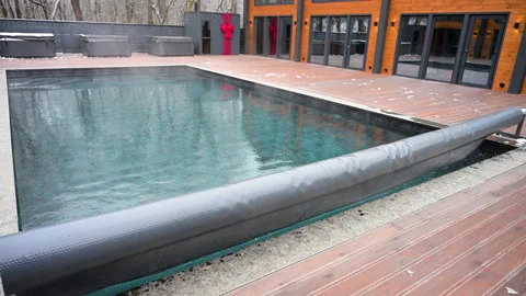 Automatic pool cover retracts to reveal outdoor swimming pool near modern house Stock Footage 345897370