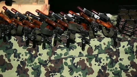 Automatic rifle with cartridges on a camouflage table Видео 83165744