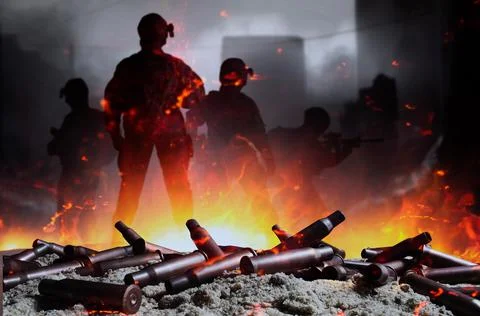 Automatic rifle gun shells laying on sand with fire and soldiers. Stock Photos