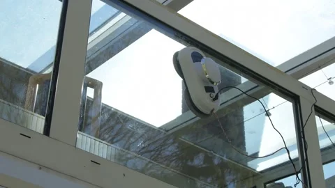 Automatic robot cleans a glass roof of a conservatory under bright sunlight. Stock Footage 336842881
