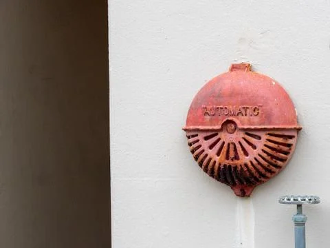Automatic rusty old fire alarm bell hanging outside of industrial building Stock Photos