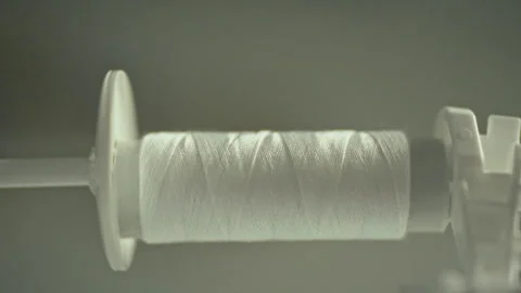 An automatic sewing machine efficiently transfers thread from a large spool Stock Footage 331315286