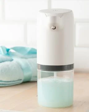 Automatic soap dispenser. In the background is a blue towel. Close-up. Light  Stock Photos