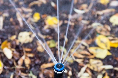 Automatic Sprinkler Spraying Water Over Garden Soil Stock Photos