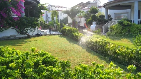 Automatic sprinkler system watering the lawn in sunshine in the garden Stock Footage 134740767