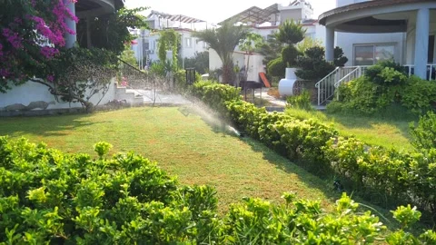 Automatic sprinkler system watering the lawn in sunshine in the garden Stock Footage 134741847
