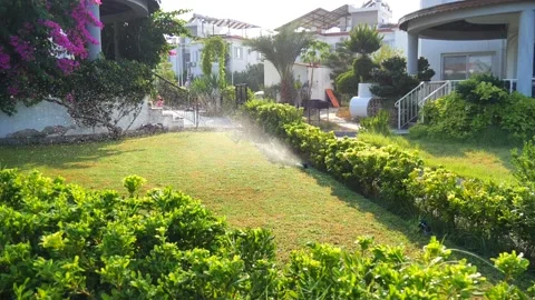Automatic sprinkler system watering the lawn in sunshine in the garden Stock Footage 134742082