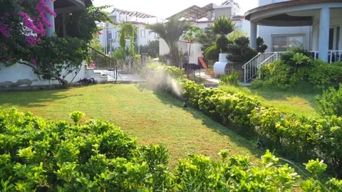 Automatic sprinkler system watering the lawn in sunshine in the garden Stock Footage 134742417