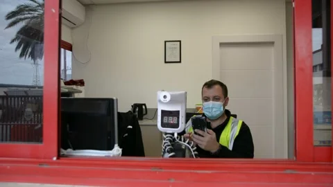 Automatic temperature measuring device and a security guard talking on the phone Stock-Footage 147056299