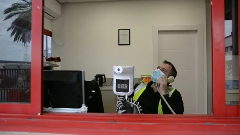 Automatic temperature measuring device and a security guard talking on the phone Stock Footage 147056961