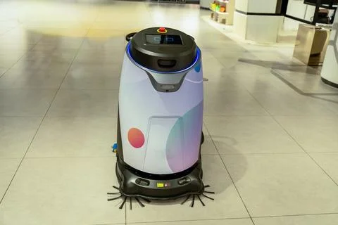 Automatic vacuum and sweeping robot are working inside the mall. Stock Photos