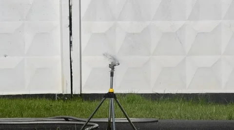 Automatic water sprinkler on background of concrete fence Stock Footage 50528694