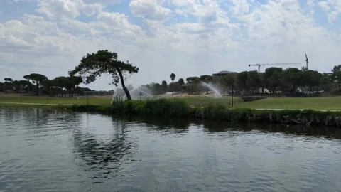 Automatic watering of grass lawns and golf courses on the river bank Stock Footage 171756324