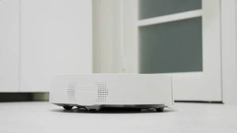 Automatic white robot vacuum cleaner cleaning floor on home Stock Footage 154410307