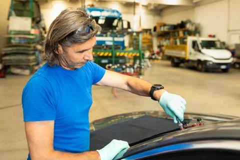 Automobile glaziers workers replacing windscreen or windshield of a car in auto Stock Photos