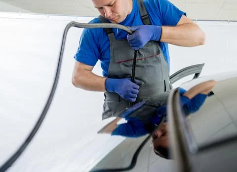 Automobile special workers remove old windscreen of a car in auto service Stock Photos