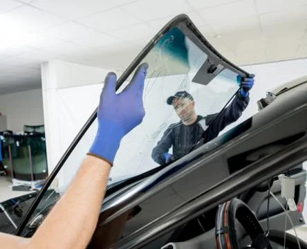 Automobile special workers remove old windscreen of a car in auto service Stock Photos