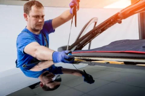 Automobile special workers remove old windscreen of a car in auto service Stock Photos