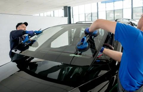 Automobile special workers replacing windscreen of a car in auto service Stock Photos