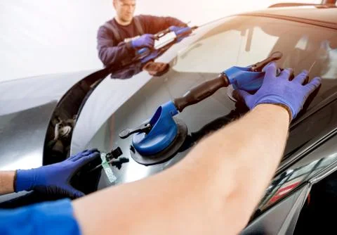 Automobile special workers replacing windscreen of a car in auto service Stock Photos