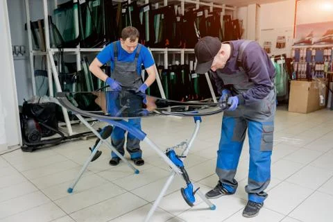 Automobile special workers replacing windscreen of a car in auto service station Stock Photos