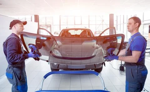 Automobile special workers replacing windscreen of a car in auto service Stock Photos