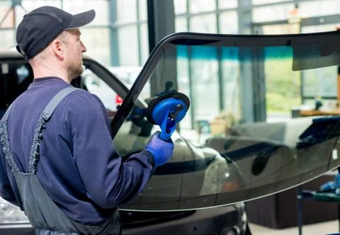 Automobile special workers replacing windscreen of a car in auto service Stock Photos