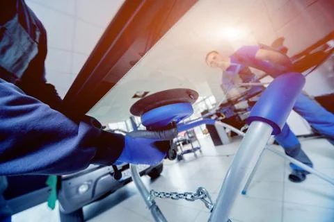 Automobile special workers replacing windscreen of a car in auto service Stock Photos