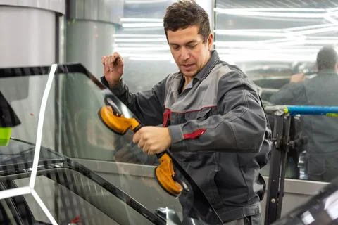 Automobile special workers replacing windscreen or windshield of a car. Stock Photos