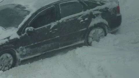 Automobile stuck in deep snowdrift during winter blizzard condition, front wheel Stock Footage 344846897