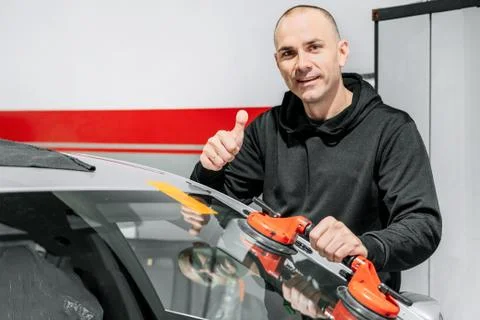 Automobile technician worker replacing windscreen or windshield of a car in auto Stock Photos