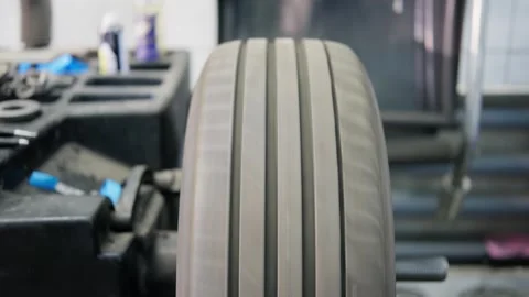 Automobile tire spinning on a balancer machine for repair in a mechanic workshop Stock Footage 339273786