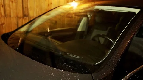 Automobile windshield with rain drops and active wipers cleaning glass at night, Stock Footage 325296348