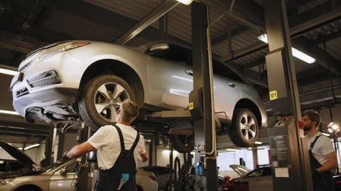 Automotive breakdown. Experts at work shop, standing in safety uniform, hold pda Stock Footage 243179984