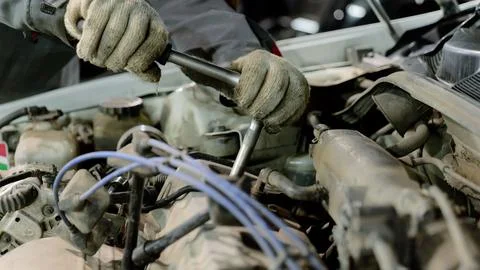 Automotive technician fixing engine component, wearing protective gloves inside Stockfoto's