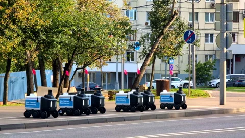 Autonomous Courier Robots for Urban Delivery Parked Beside Tree Lined Road Stock Footage 345964079