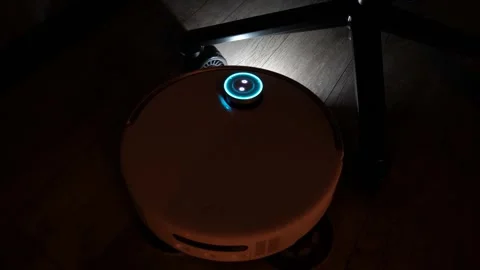 Autonomous robotic vacuum cleaner operating in a dimly lit residential room Stock Footage 345023890