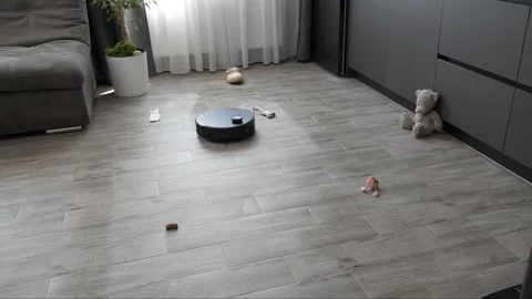Autonomous robotic vacuum navigates across a gray tiled domestic floor surface Stock Footage 345023883