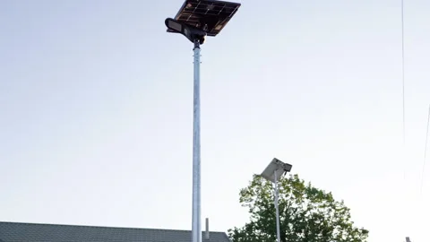 Autonomous solar-powered lighting fixture on tall pole, showcasing gradual Video stock 318715685