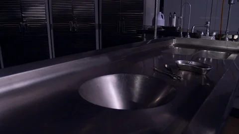 AUTOPSY TOOLS SIT UPON AN AUTOPSY TABLE.  EMPTY MORGUE.  4K, 10 BIT SLIDER SHOT. Stock Footage 100200783