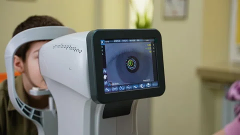 Autorefractor performing eye examination on young patient Stock Footage 310805536