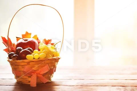 Autumn background with basket with yellow maple leaves, grapes, red apples. F Stock Photos