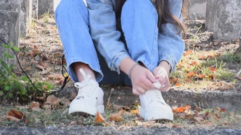 Autumn . Close-up white sneakers and girl ties shoelaces  . Comfortable and spor Stock Footage 252198112