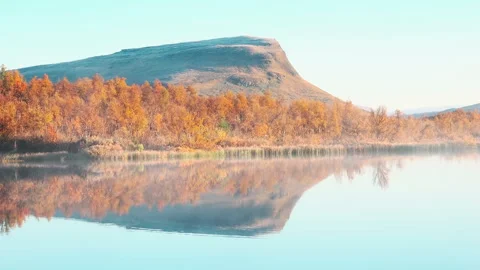Autumn colors reflect on still lake with mountain backdrop Stock Footage 314842753