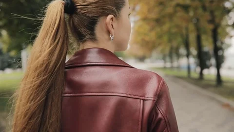Autumn is coming. Woman in burgundy jacket walk in city street, slowmotion, rear Stock Footage