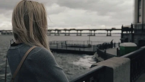 Autumn is coming. Woman near river, the wind blows her hair, autumn cold cloudy Stock Footage