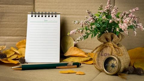 Autumn composition with a notebook, compass, flowers, and leaves. Stockfoto's